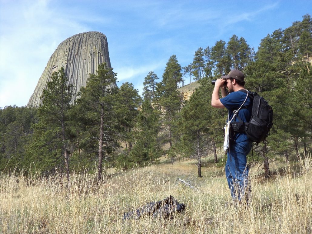 Jake Hourt conducts an IMBCR point count in the shadow of Devil’s Tower in 2014. Photo by Nick Van Lanen.
