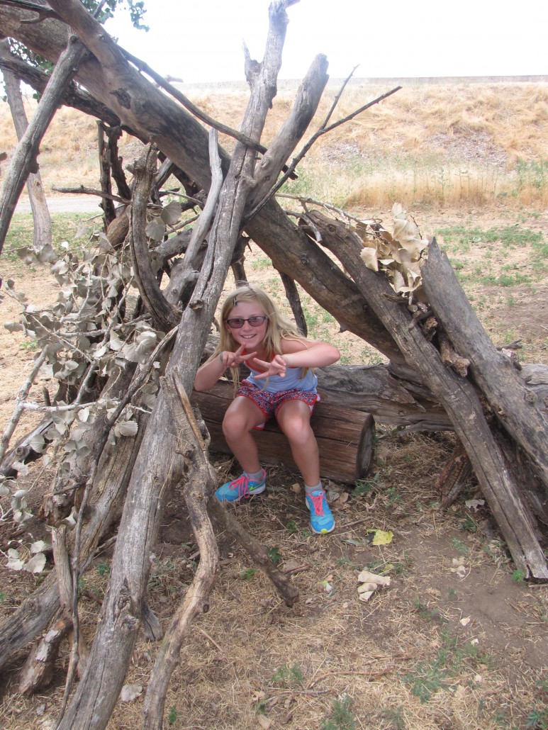 Sky and Earth Day Camper in a fort that they built at the Old Stone House while learning about habitat.